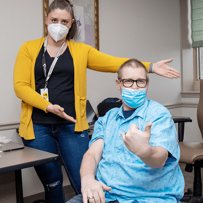 Nurse Jessica Weston and STC Member Lee Luety give the camera a "ta-da" pose after Luety received his Covid-19 vaccine.
