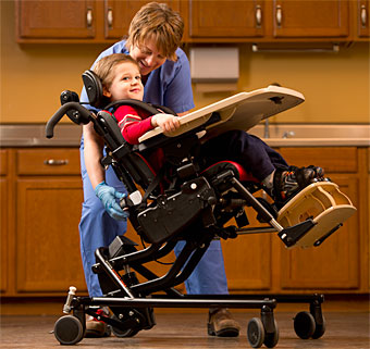 A child in an adaptive positioning chair with a therapist